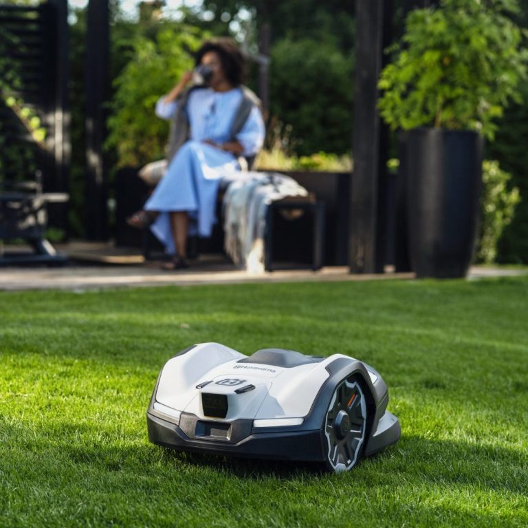 Mehr Freizeit mit Husqvarna Automower Mähroboter Husqvarna Automower Mähroboter mäht auf Rasen, mit Frau auf Gartenbank